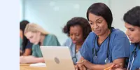 A row of healthcare professionals working on laptops and taking notes