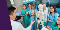 A group of smiling healthcare professionals examining a skeleton model