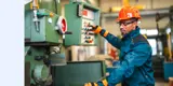 A man wearing a hardhat and working on machinery